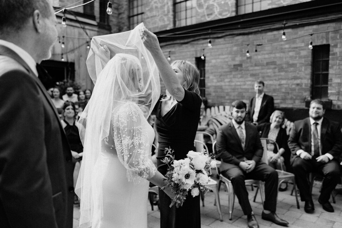The mother of the bride lifting the bride's veil as part of the wedding ceremony