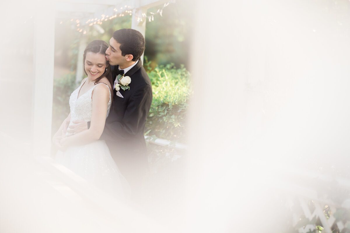 Groom kissing bride on forehead through window