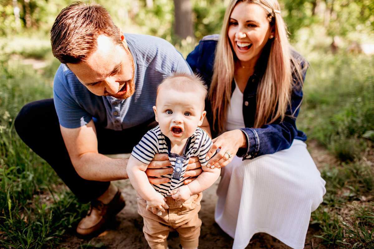 Baby boy  standing with the help of his parents during family photos in Toronto park