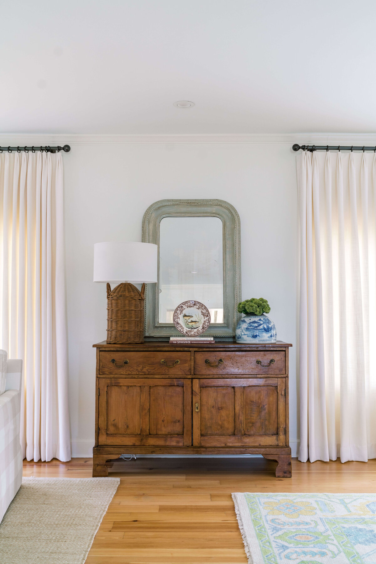oyster creek studios happy valley white chairs around a wooden dining room table with white and green rug wooden bureau with wicker lamp and decorative platter