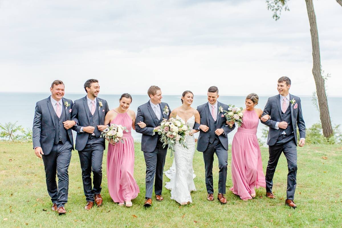 bridal party walks together with arm intertwined