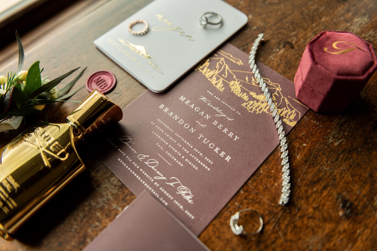 Burgundy wedding details including invitations , jewelry, and perfume.