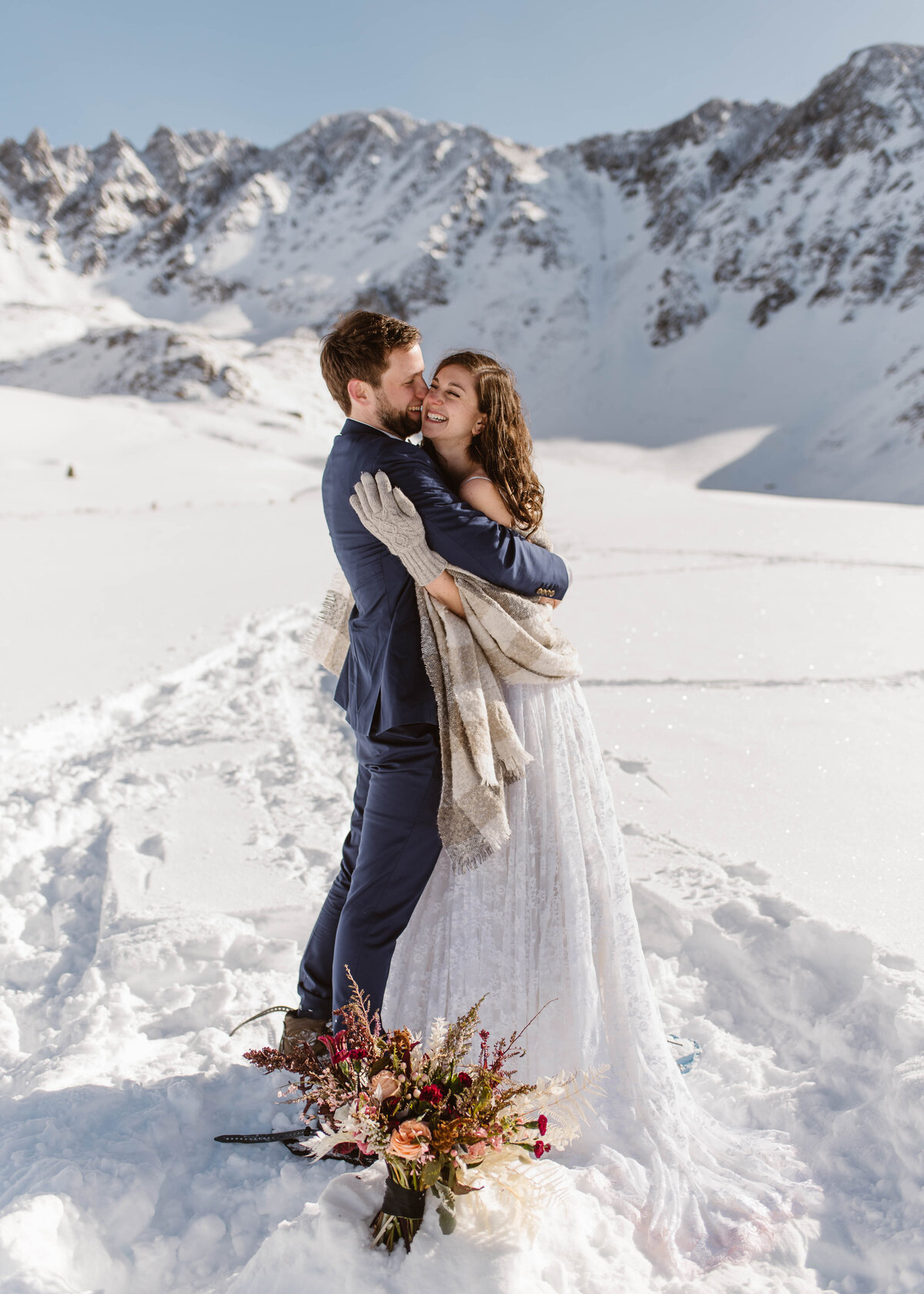 Couple hugs as they laugh during their snowshoeing elopement to Mayflower Gulch, Colorado