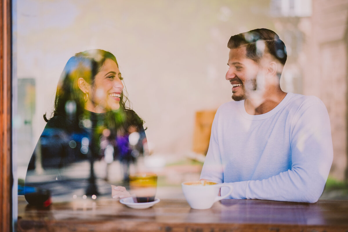 An engaged couple having coffee together in front of a window on nassau st near princeton university nj