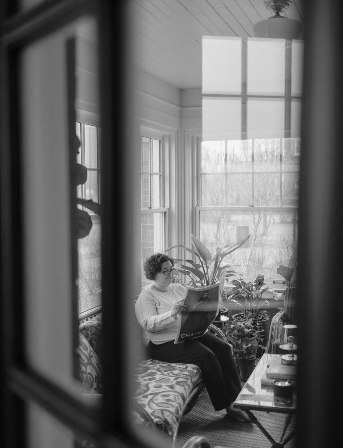 web designer reads newspaper in sunroom with plants, ALEO Detroit