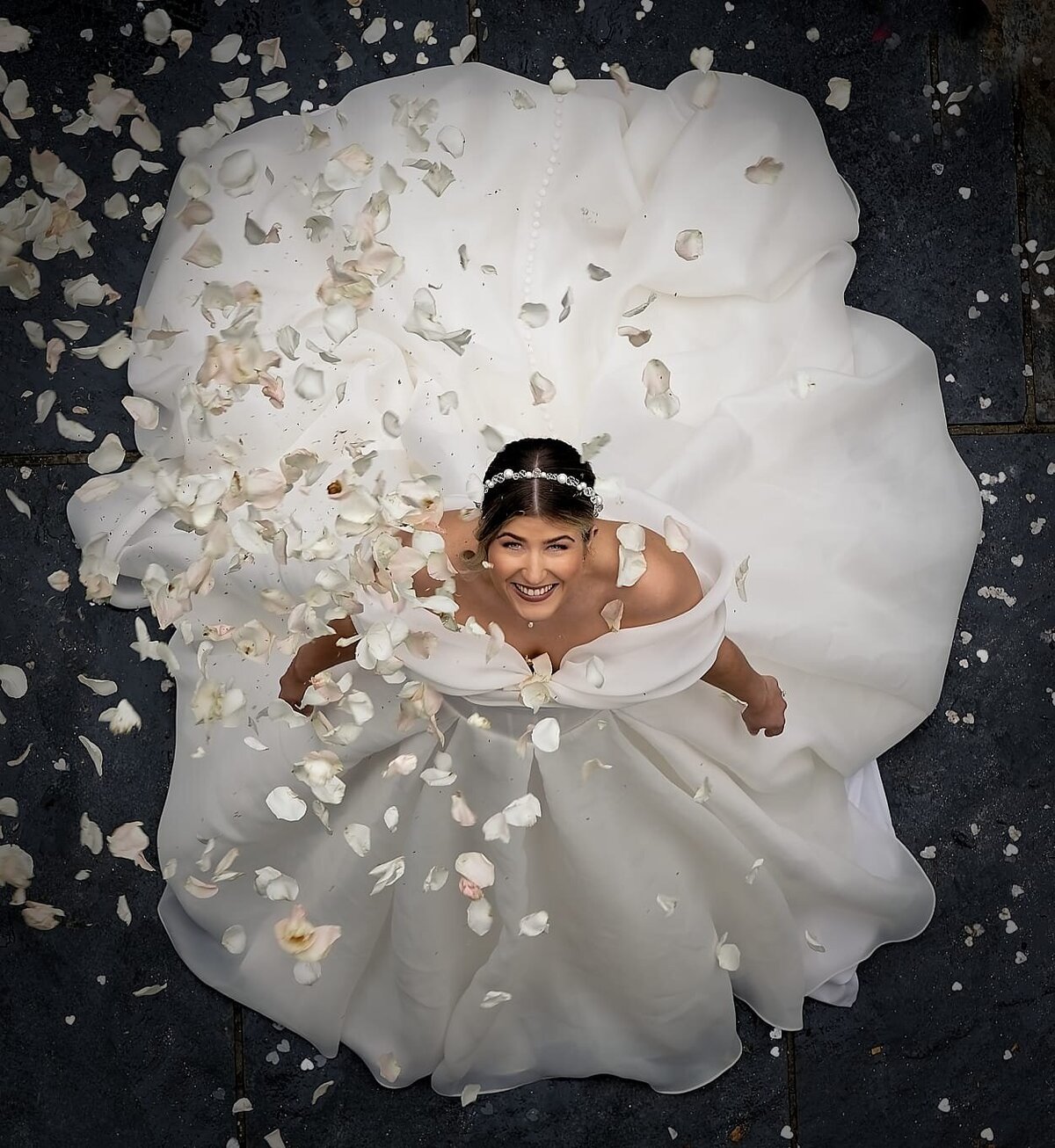 photo from above of a bride in a white wedding dress looking up at the camera and smiling