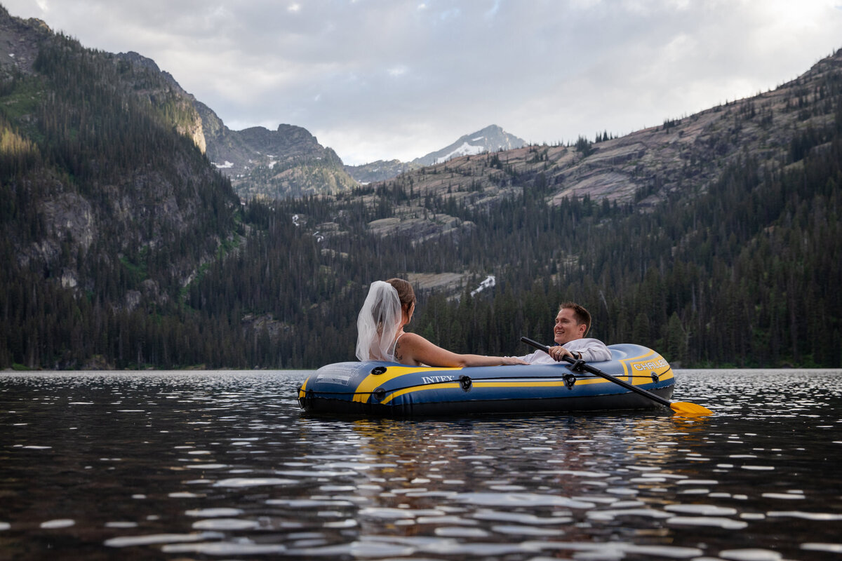 A bride and groom paddle around a lake in Montana as their Montana elopement photographers capture every moment.