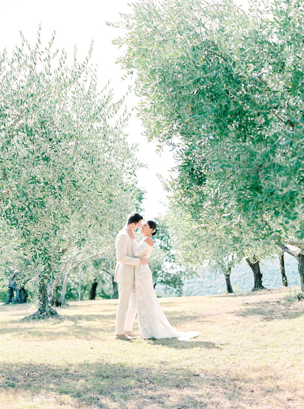Film photograph of Bride and groom embracing among the olive trees photographed by Italy wedding photographer at Villa Montanare Tuscany wedding