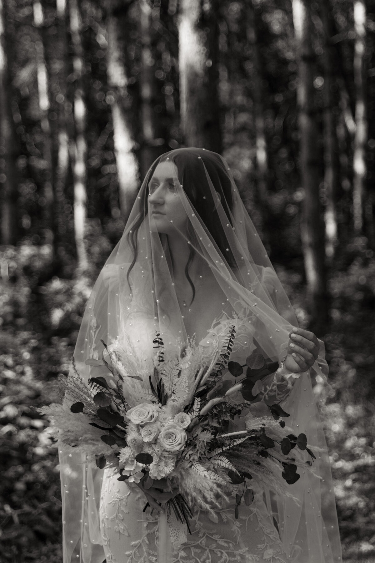 Black and White Photo of bride in the woods with her veil over her head