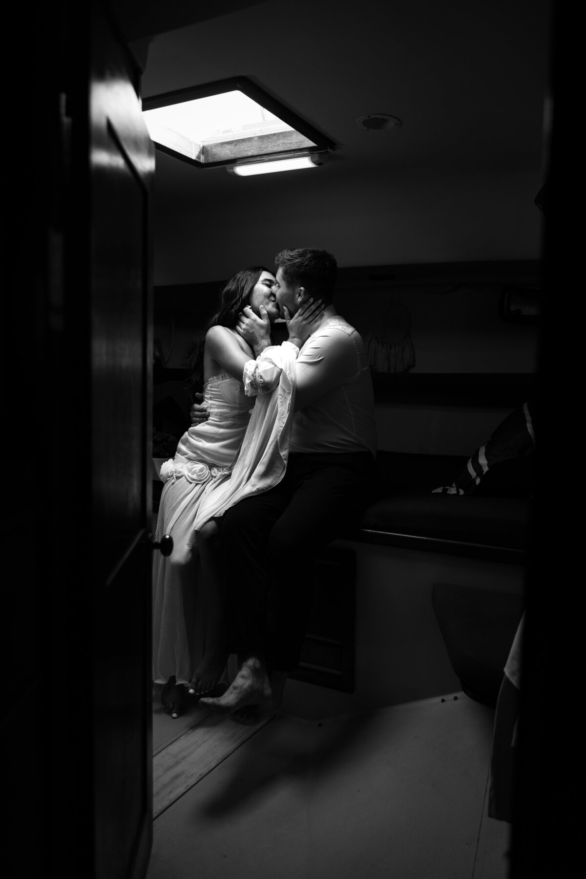 Shannon Lee, from Love Like Wild Photography, captures an intimate black-and-white moment of a couple sharing a close embrace indoors.