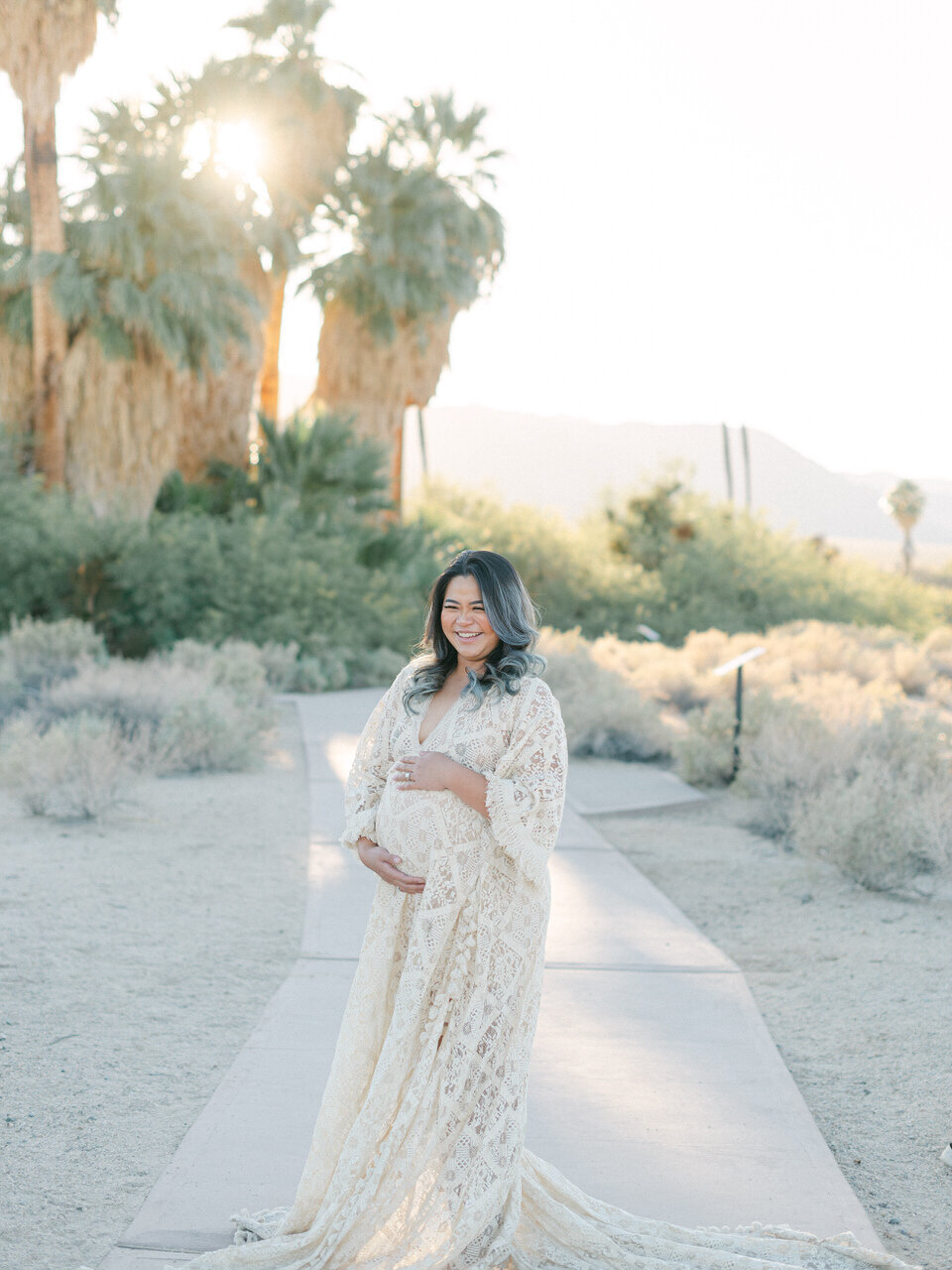 A glowing mother-to-be in a delicate lace gown at a desert location in Twenty-Nine Palms, CA, captured in a refined editorial style by Elizabeth Kane Photography—serving Philadelphia, New York, and DC.