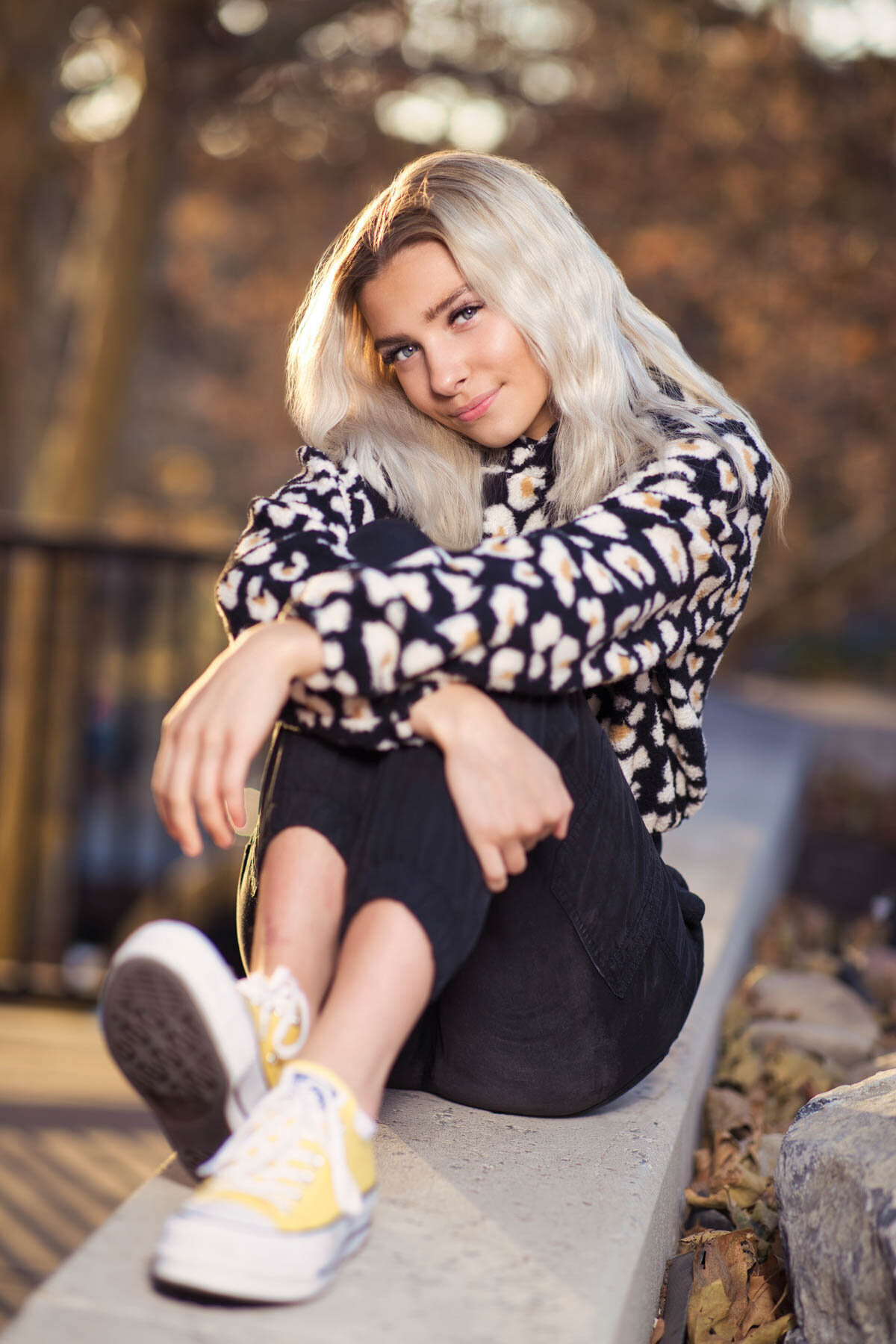 Girl sitting on concrete wall for senior photos during a shoot at Trolley Square in Utah.