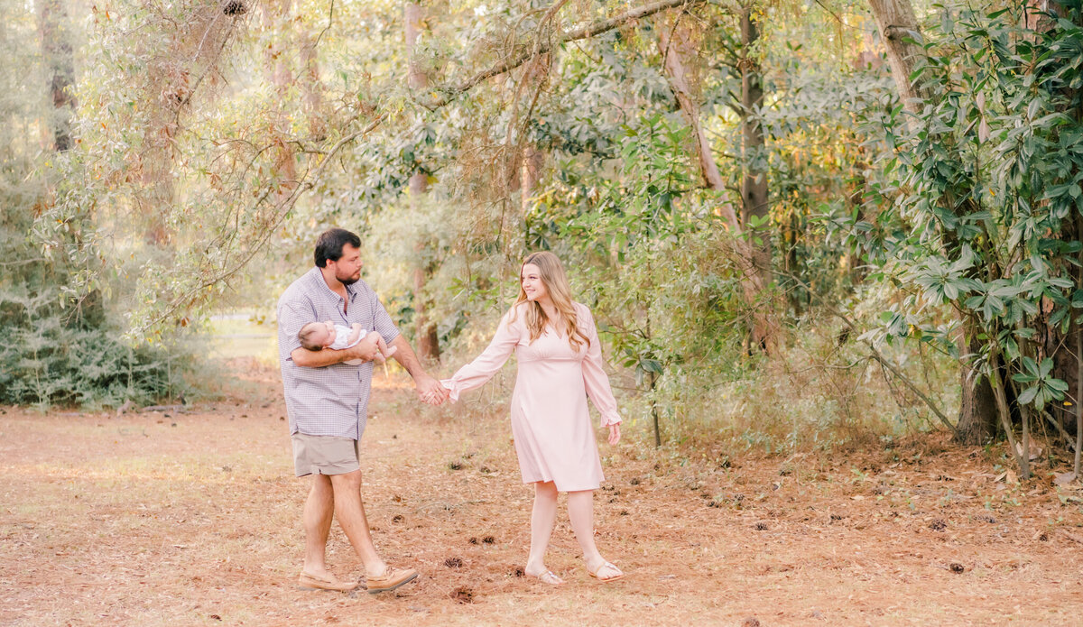 dad holding baby girl while holding hands with mom on a path on a college campus