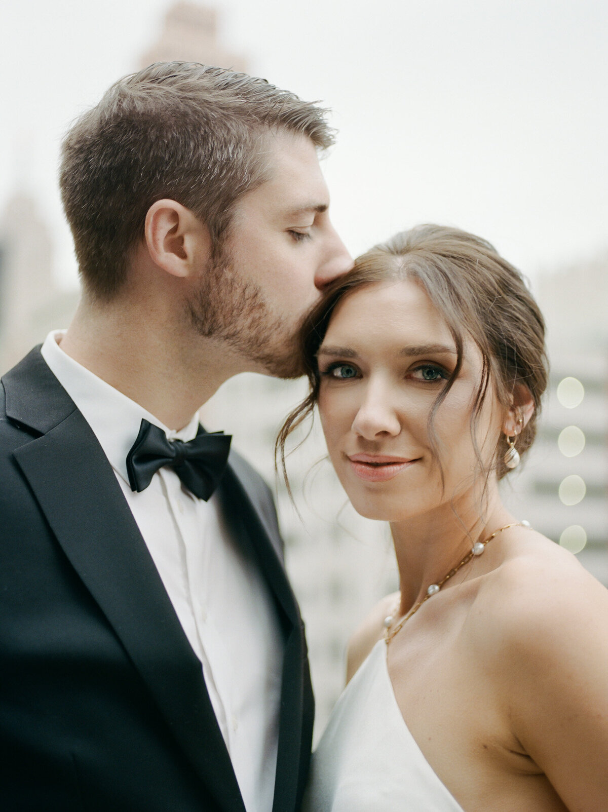 groom kisses bride as she gazes at camera, soft, natural film wedding photography in Michigan