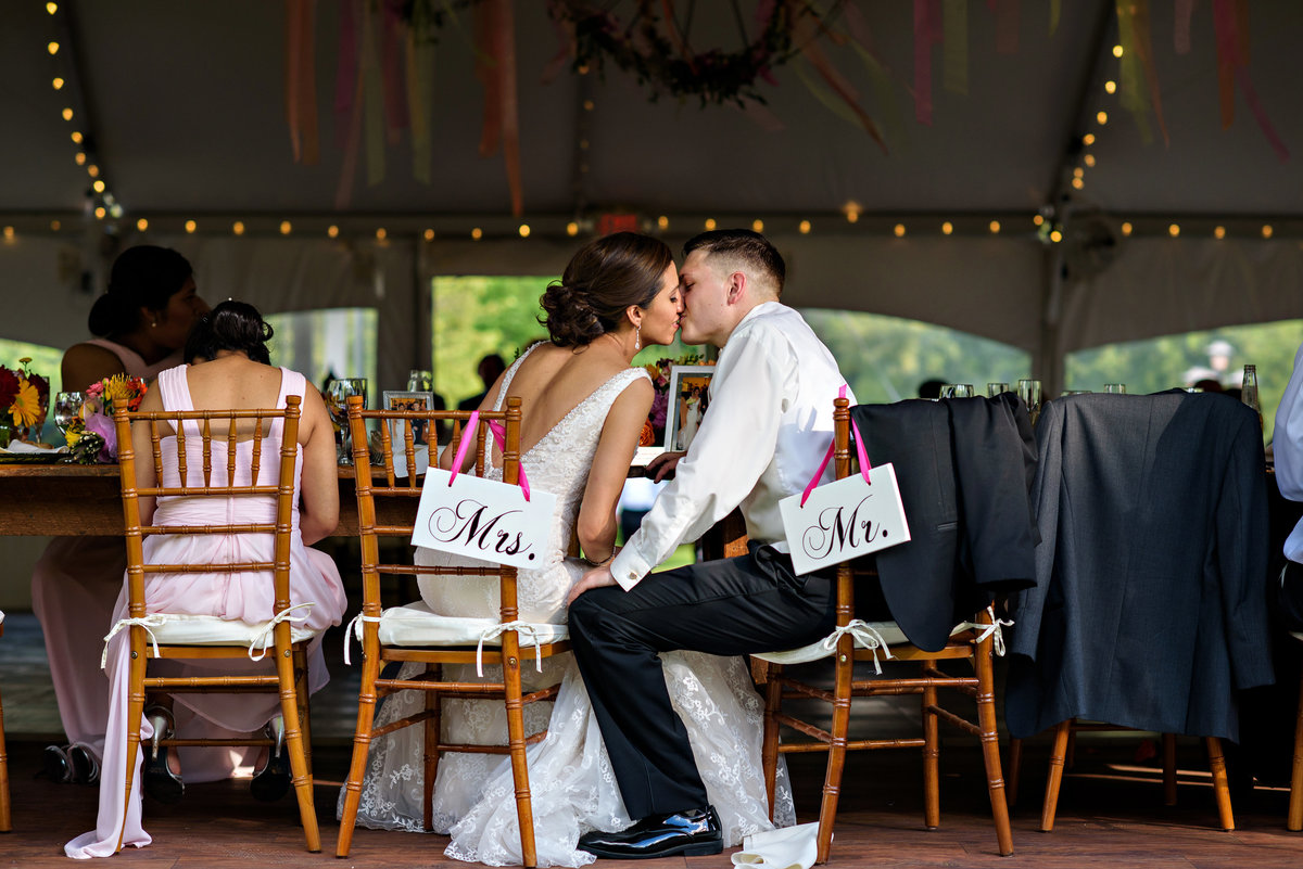 A bride and groom kiss at their wedding table during the reception at Pearl S Buck Estate.