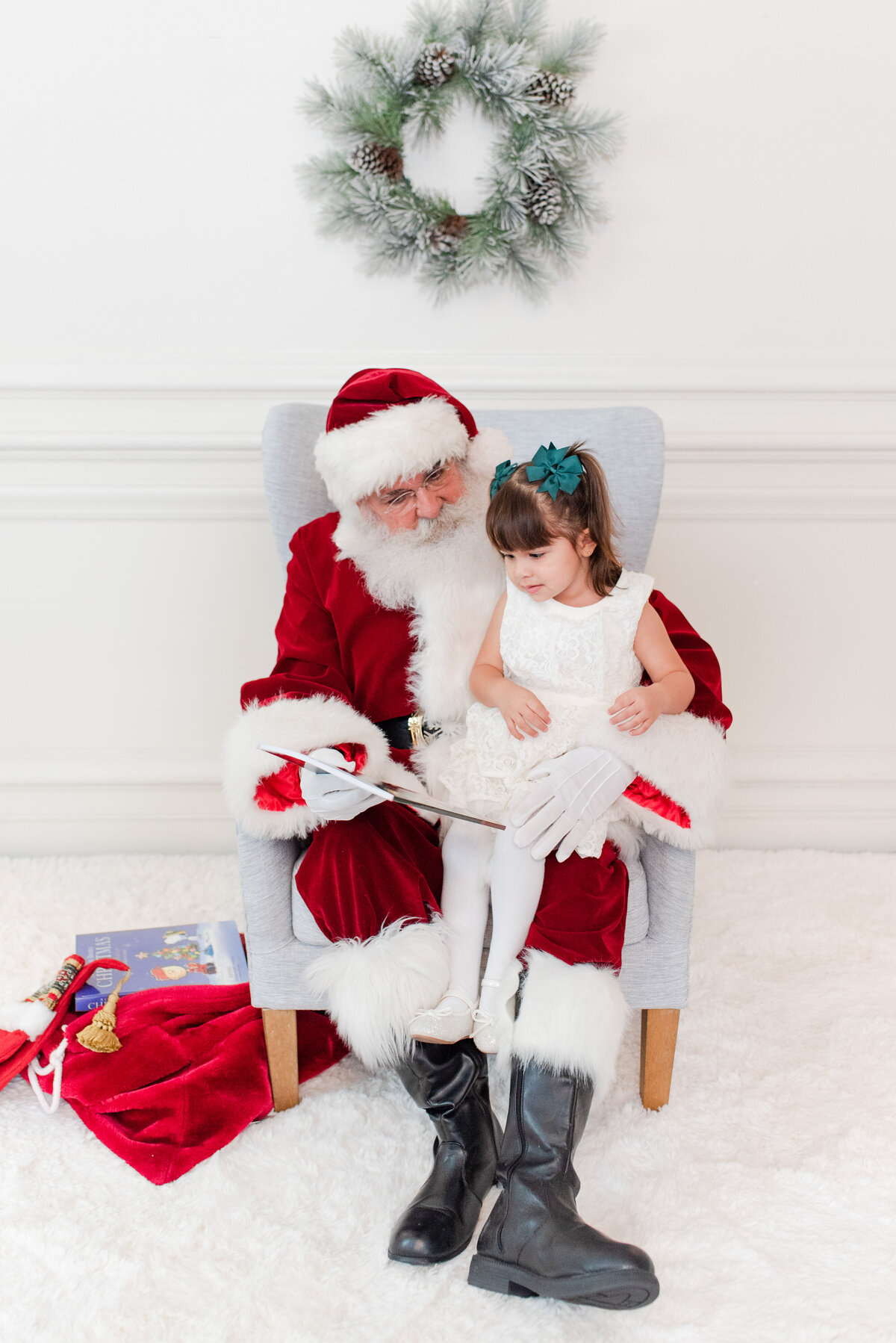 santa reading a book with a toddler toddler siblings brother and sister jumping on the bed with snow and pajamas by miami christmas mini session photographer msp