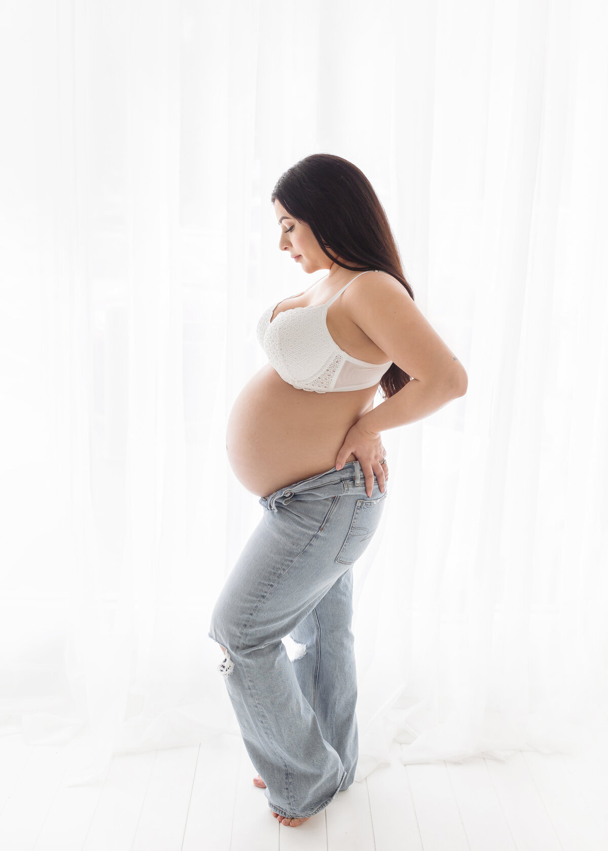 pregnant woman in jeans and bra