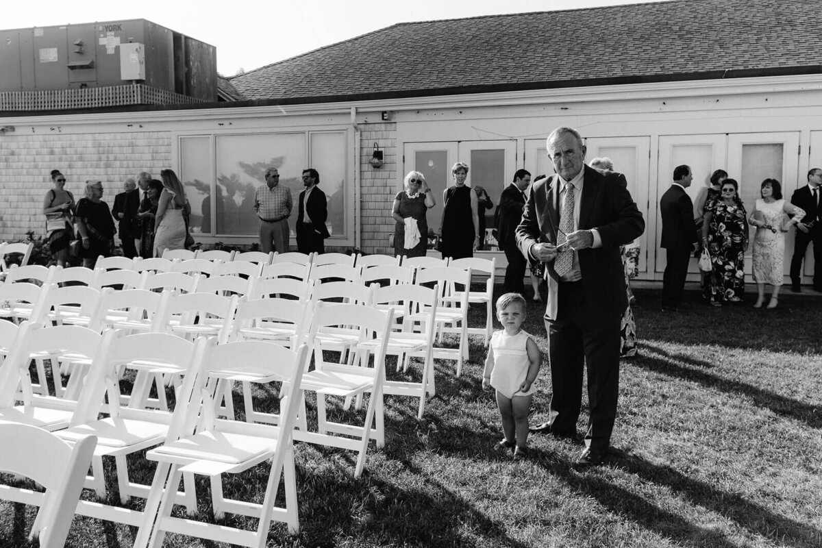 Black and white photo of a baby, an old man in a suit, and other guests in a wedding at Cape Cod, Osterville, MA.