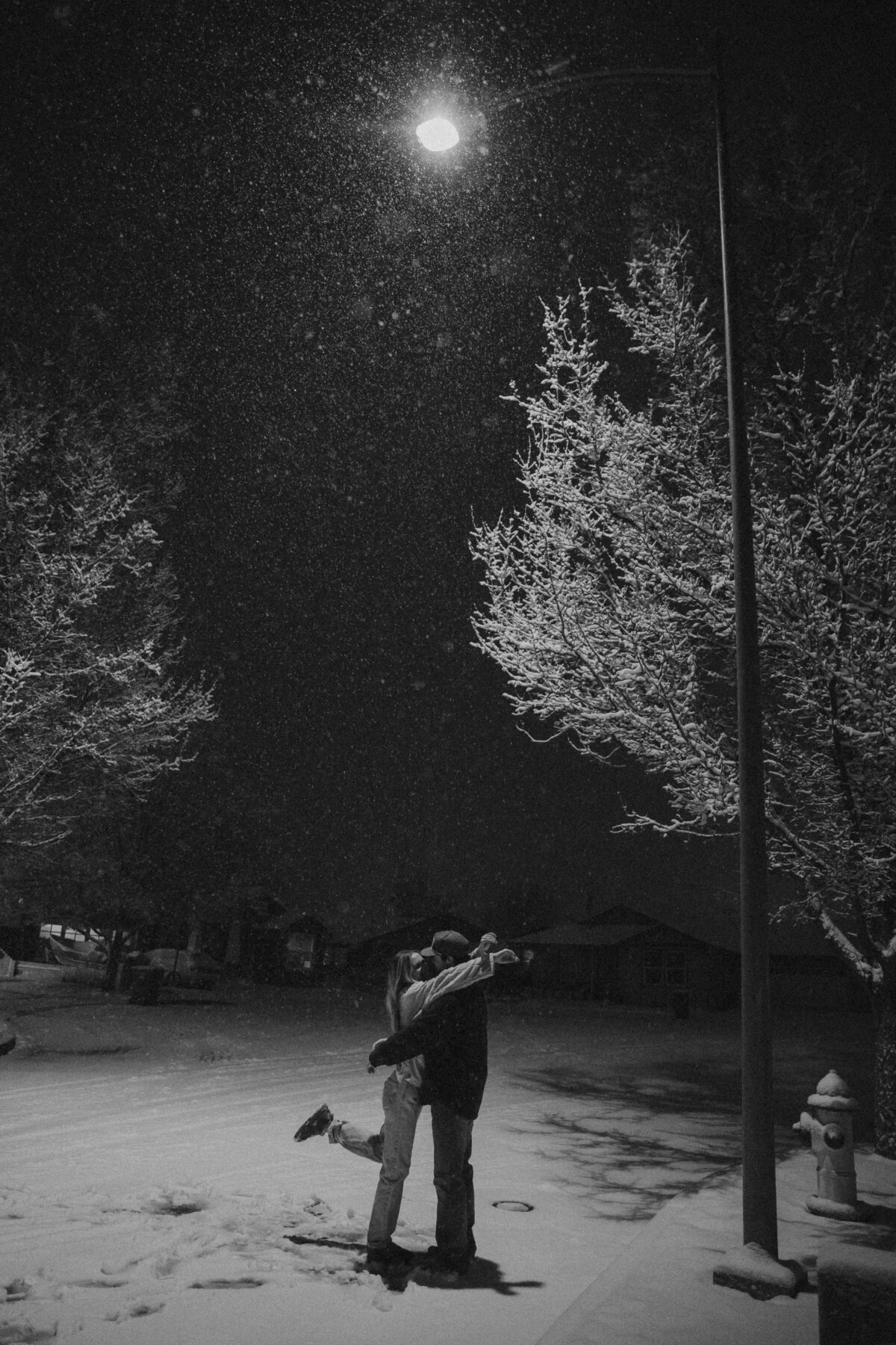 Romantic Winter Couples Photo Kissing Under Streetlight as Snow Falls