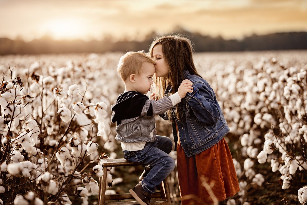 Big sister kissing baby brother in a Georgia cotton field. Photographed by fall mini session photographer near Atlanta, GA. 