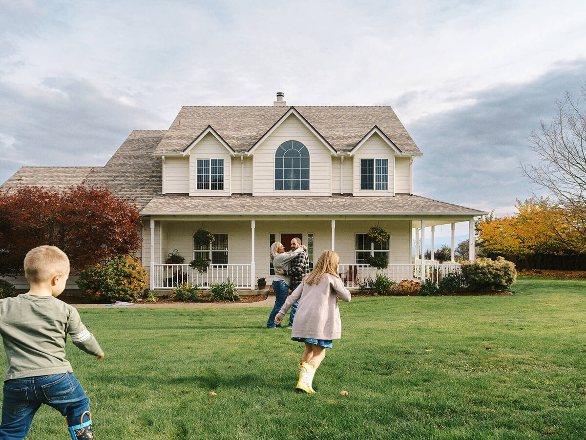 A family plays outdoors in front of their house during a family photo shoot shot by Among the Oaks Photography.