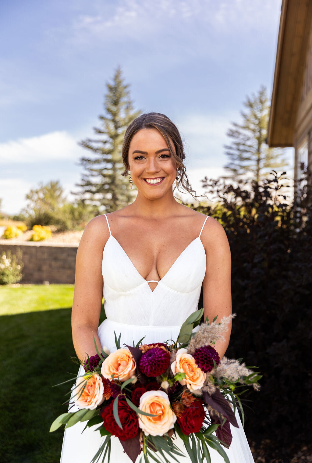 Bride poses with her burgundy and peach bouquet.