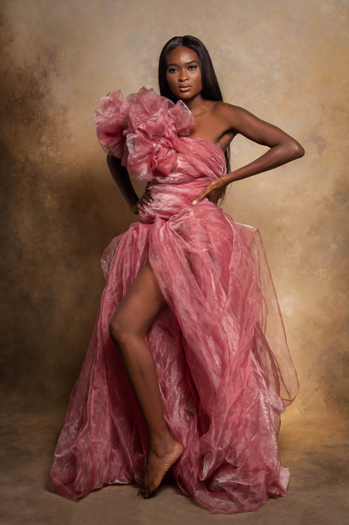 A black woman posing with a pink tulle dress showing her left leg