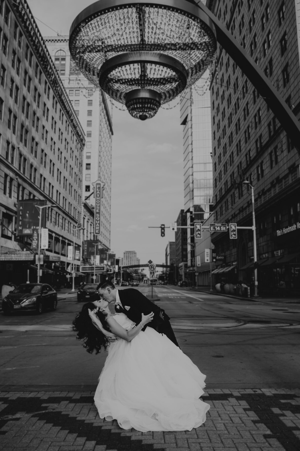 Groom dips bride under chandelier