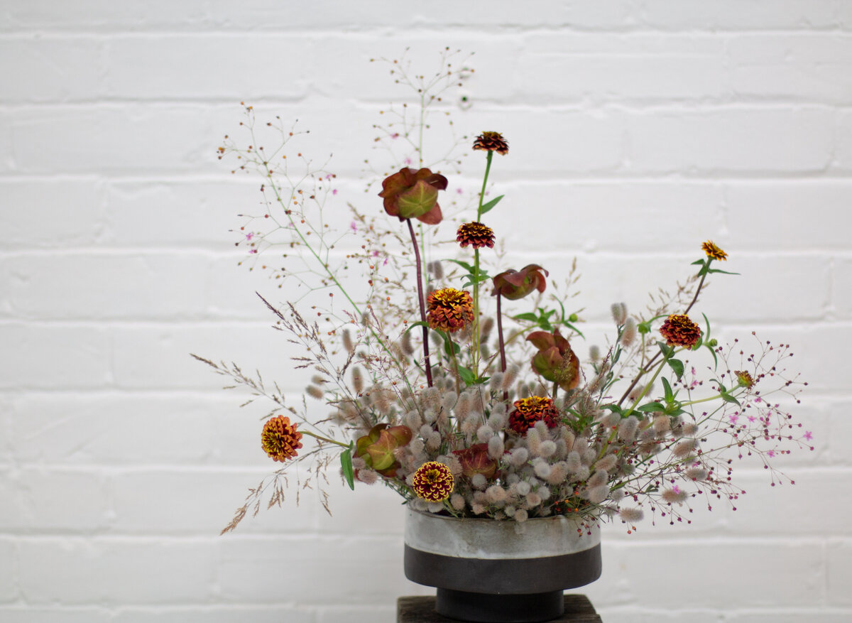 A modern arrangement of orange flowers and autumn greenery at a Montreal wedding.