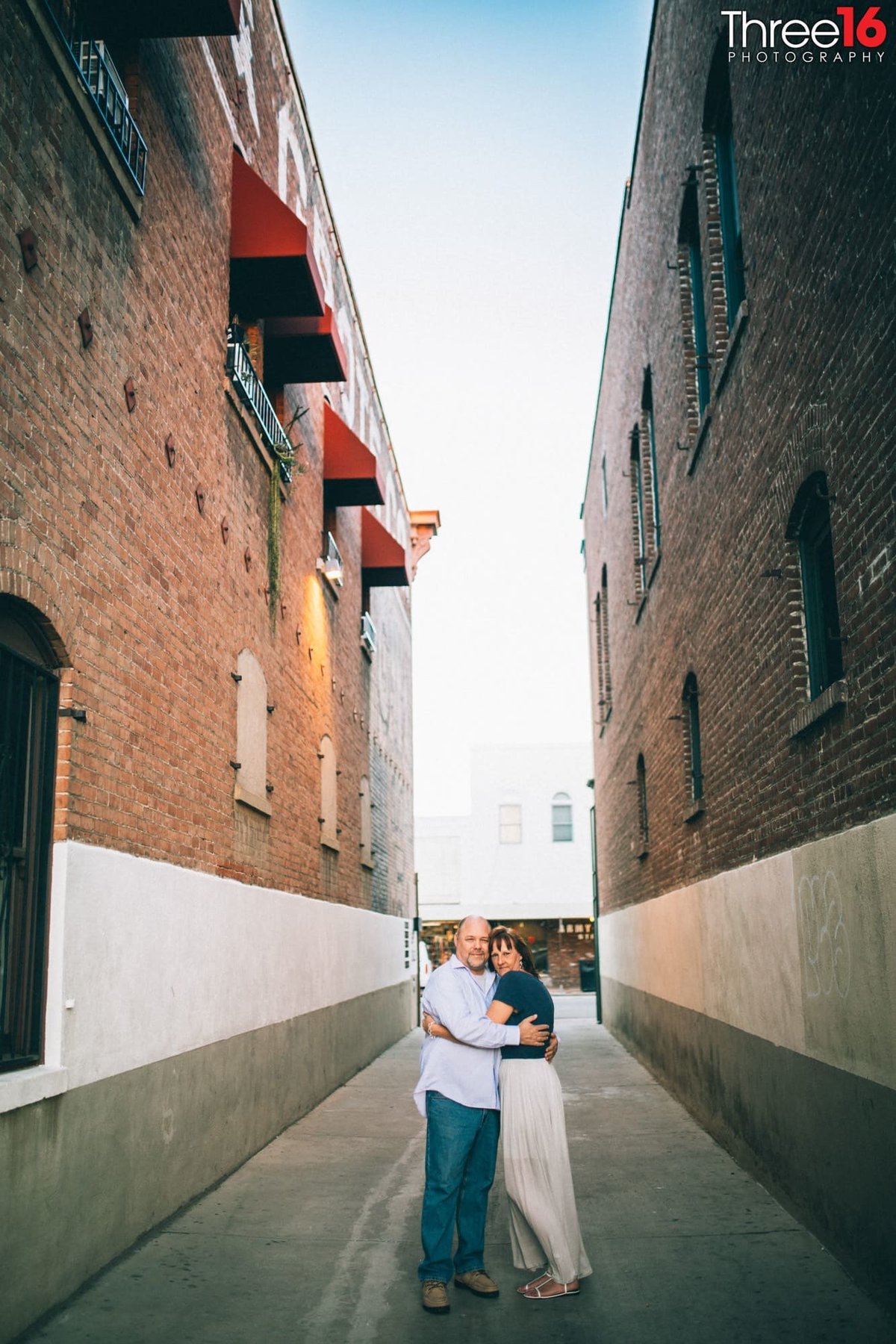 Engaged couple embrace one another in an Old Towne Orange alleyway