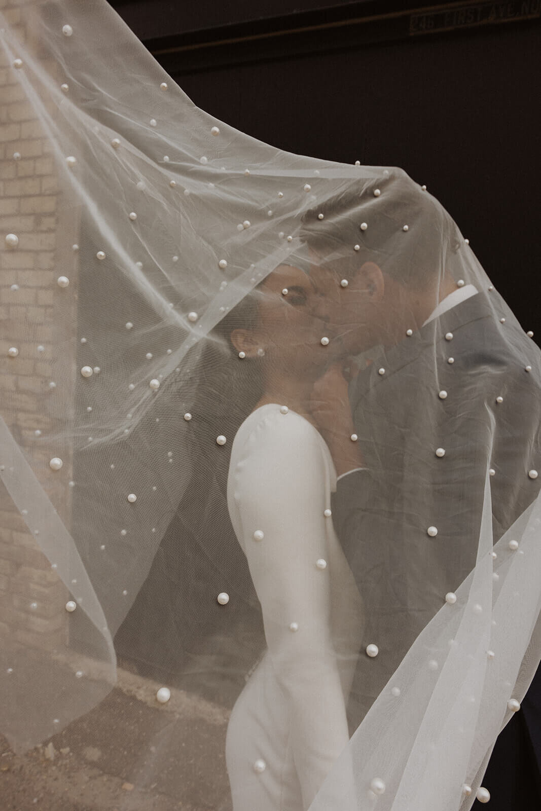 Minnesota bride and groom kiss under the cover of pearl-detailed veil