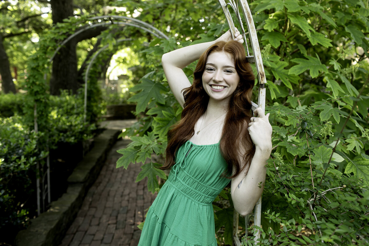 A senior poses in a sleek outfit, with a bright smile lighting up the frame