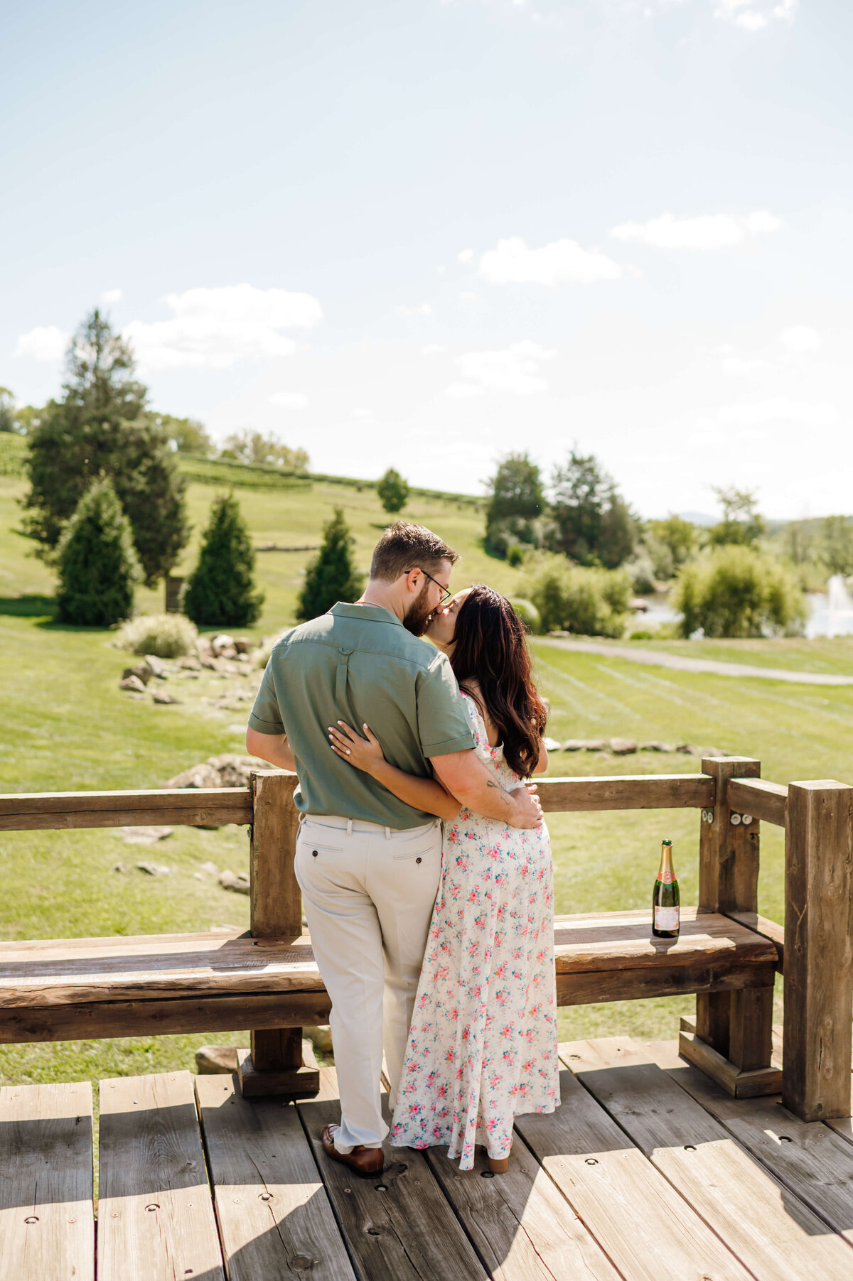 man and woman standing together and looking out at a vineyard wedding venue in Virginia holding one another with their arms around each others waists while kissing