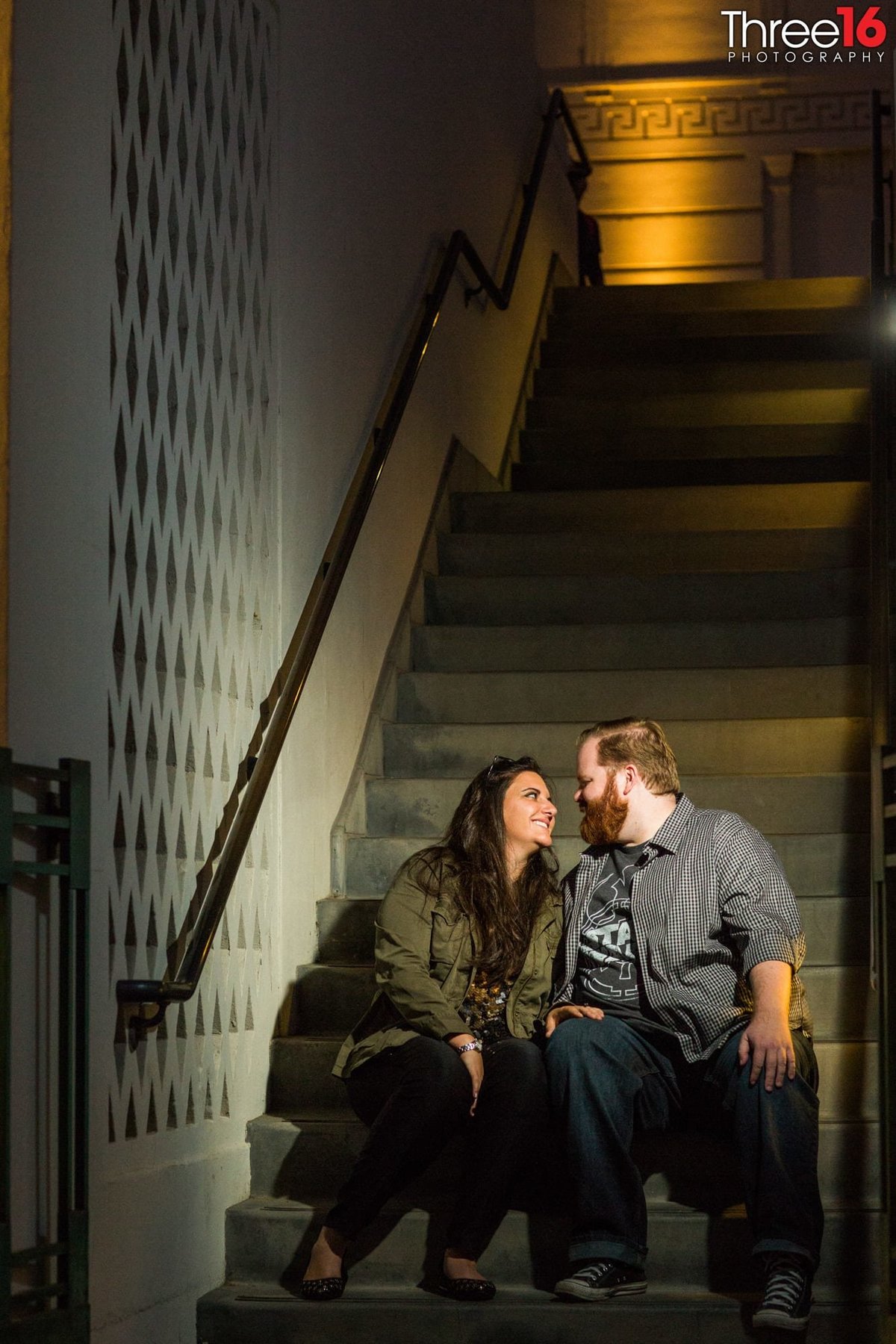 Engaged couple have big smiles as they sit on the stairs