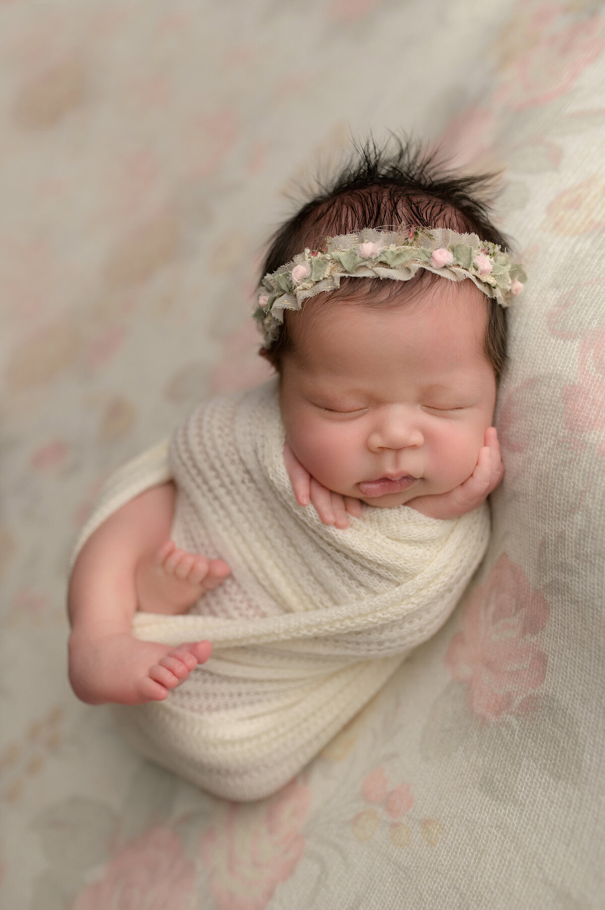 Swaddled newborn with hand on cheek