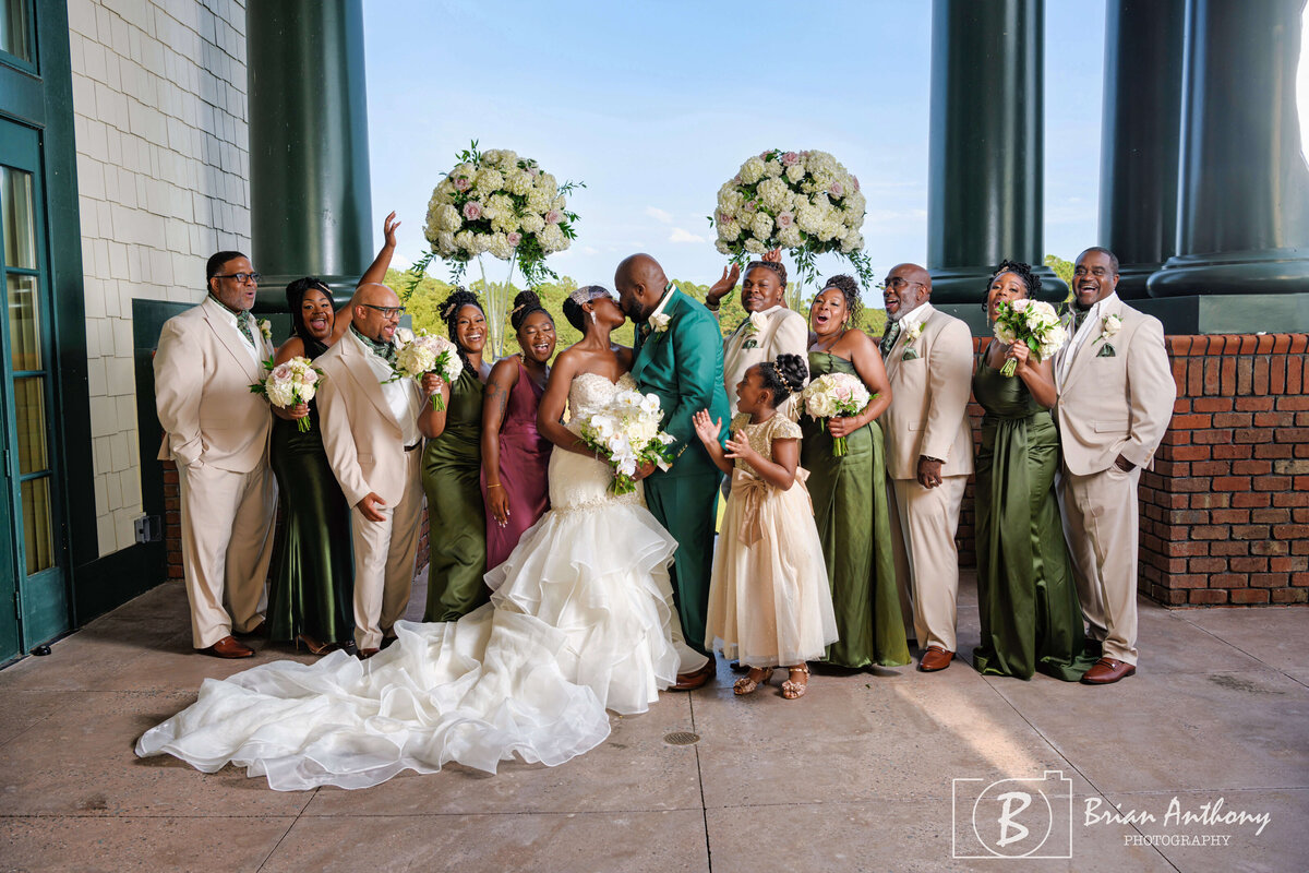 Stylish wedding party celebrating with the bride and groom in coordinated emerald green outfits.