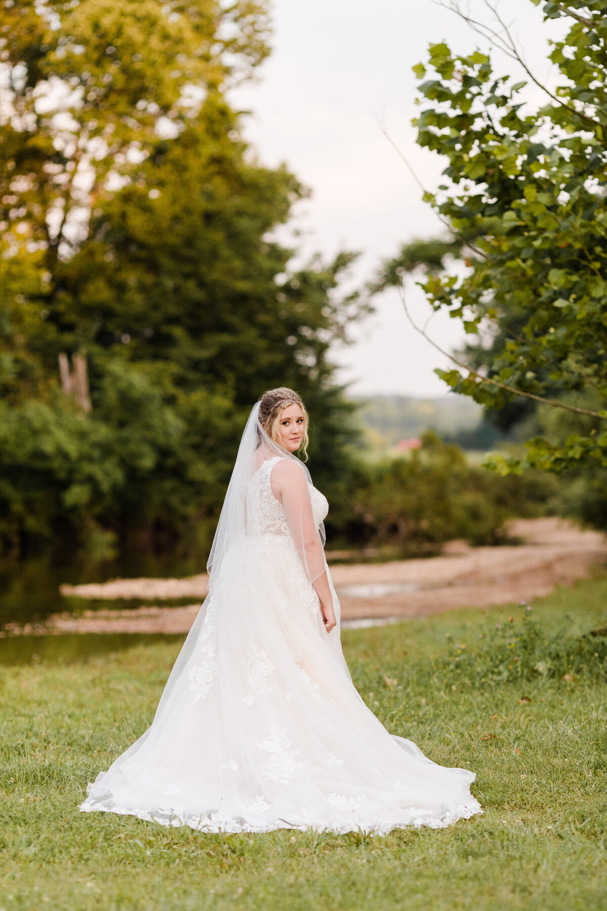 Bride looking over her shoulder at camera wearing a lace dress