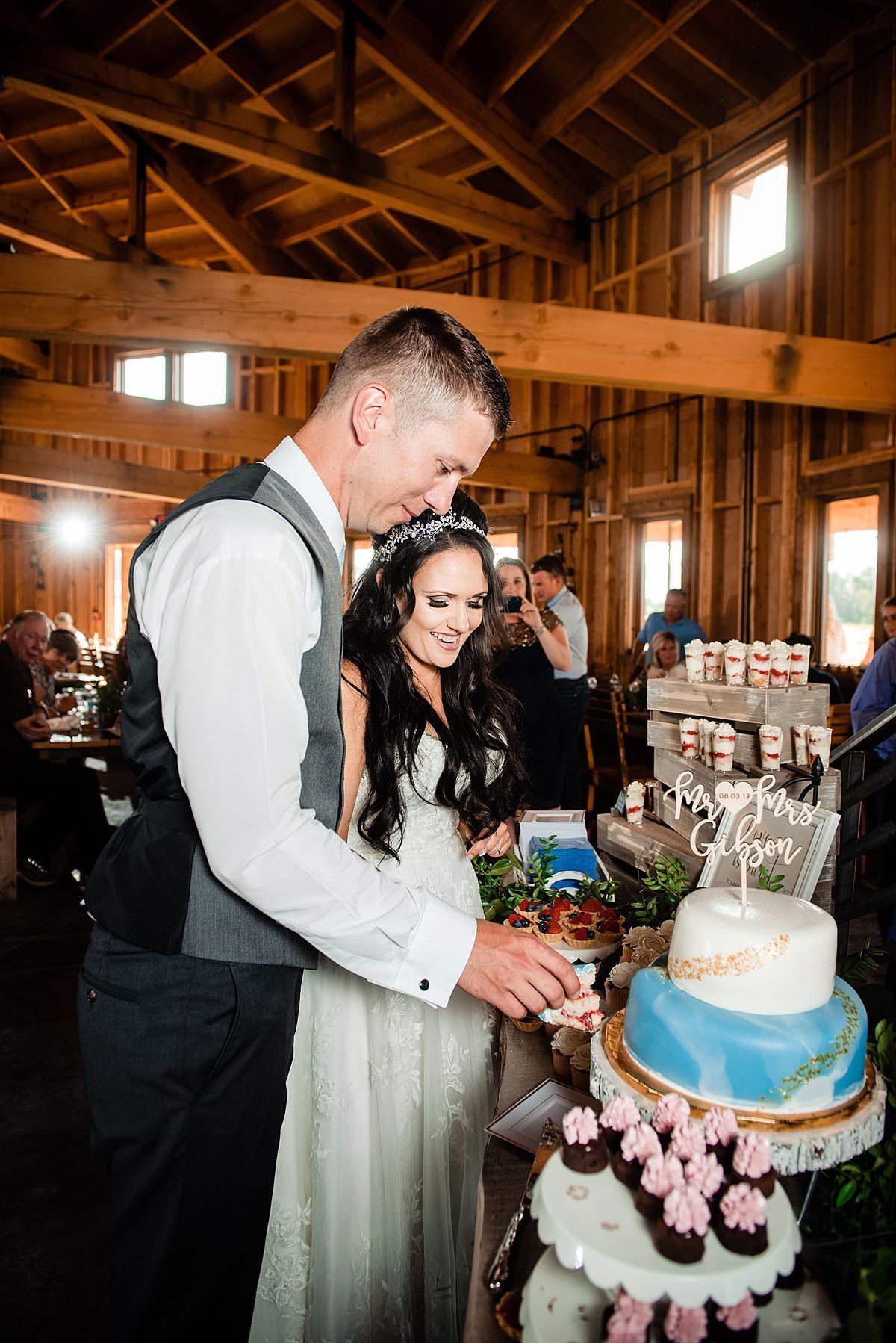 Bride and groom cutting their wedding cake inside of the barn