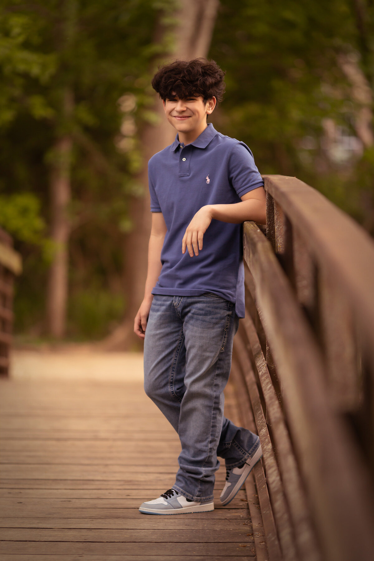 A young man casually poses on a bridge for family portraits, captured by a Dallas family photographer, highlighting natural charm.