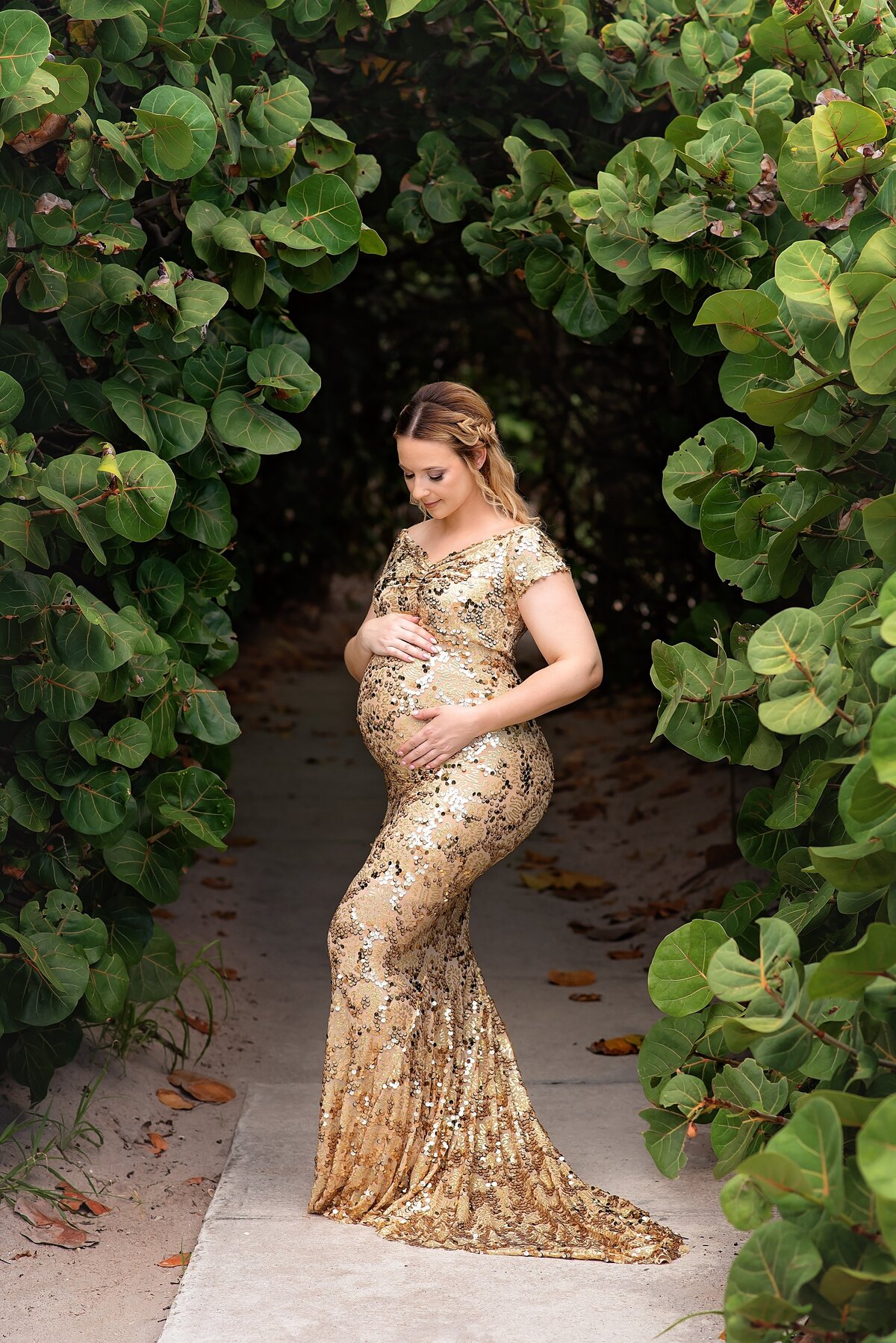 Jupiter outdoor maternity photoshoots near me at Coral Cove Beach with an elegant dress in a beautiful greenery arch.
