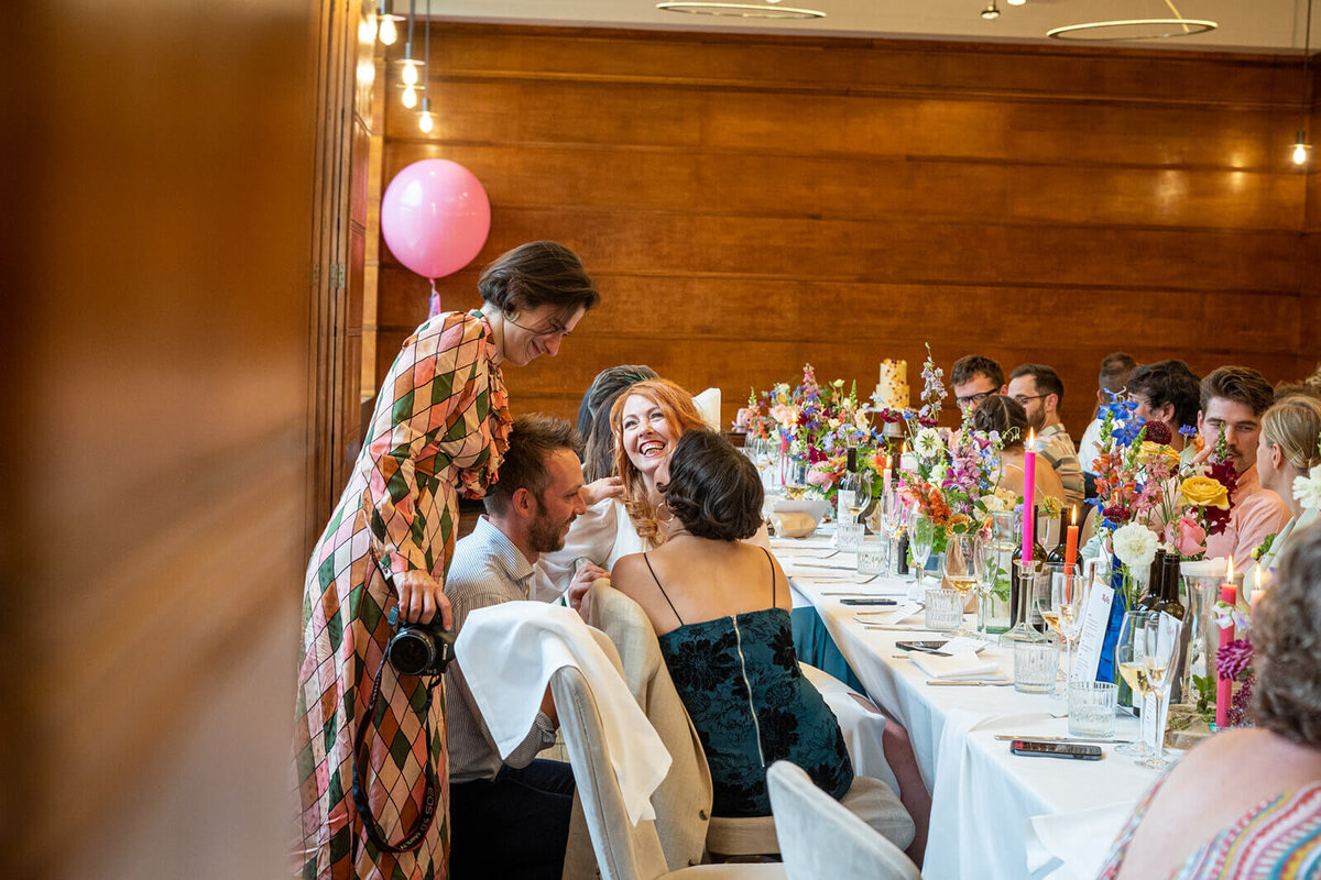Bride laughing with friends at wedding breakfast in Bethal Room Town Hall Hotel London