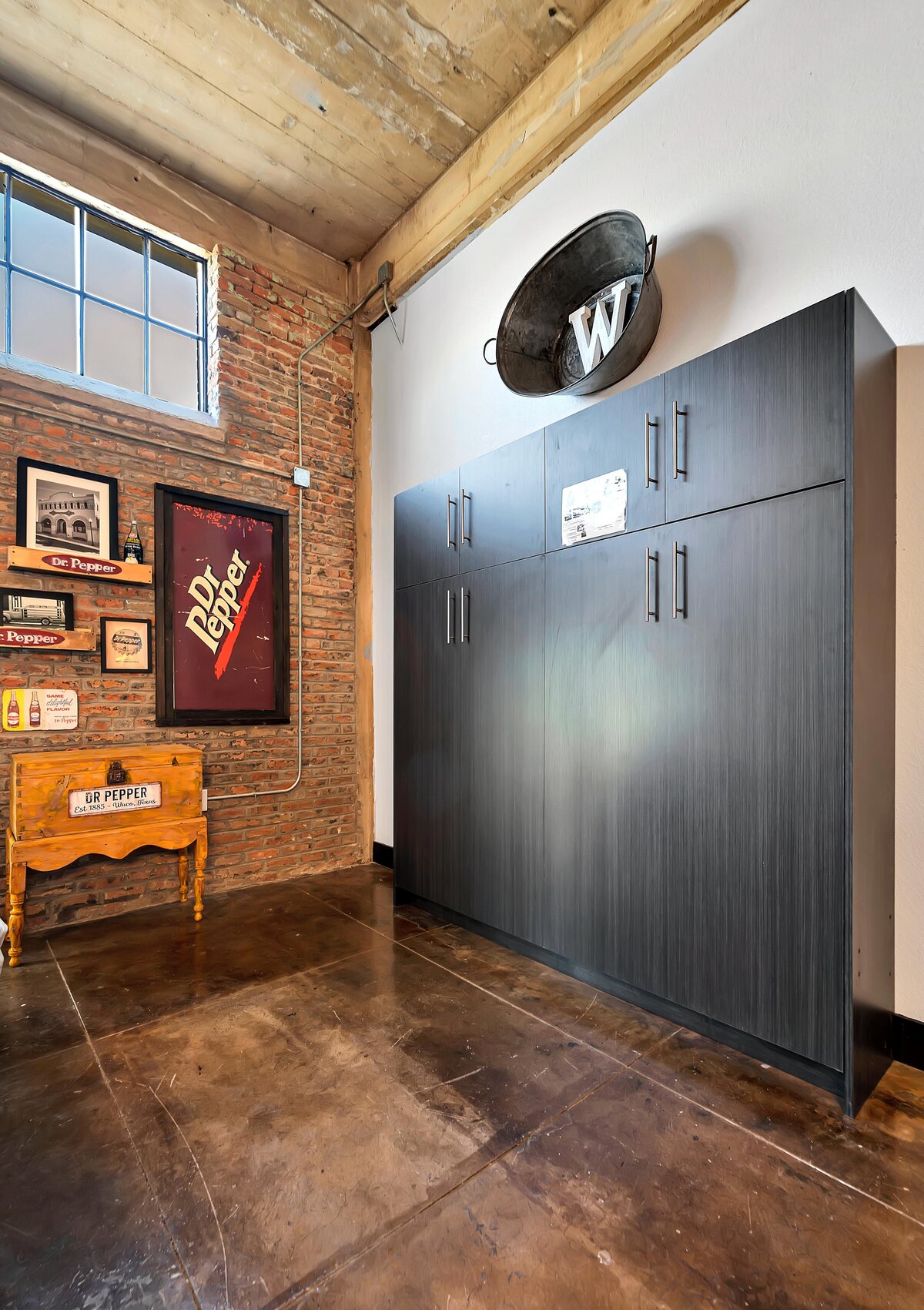 Queen size Murphy bed in the living room of this one-bedroom, one-bathroom vintage industrial condo with Smart TV, free Wi-Fi, and washer/dryer located in downtown Waco, TX.