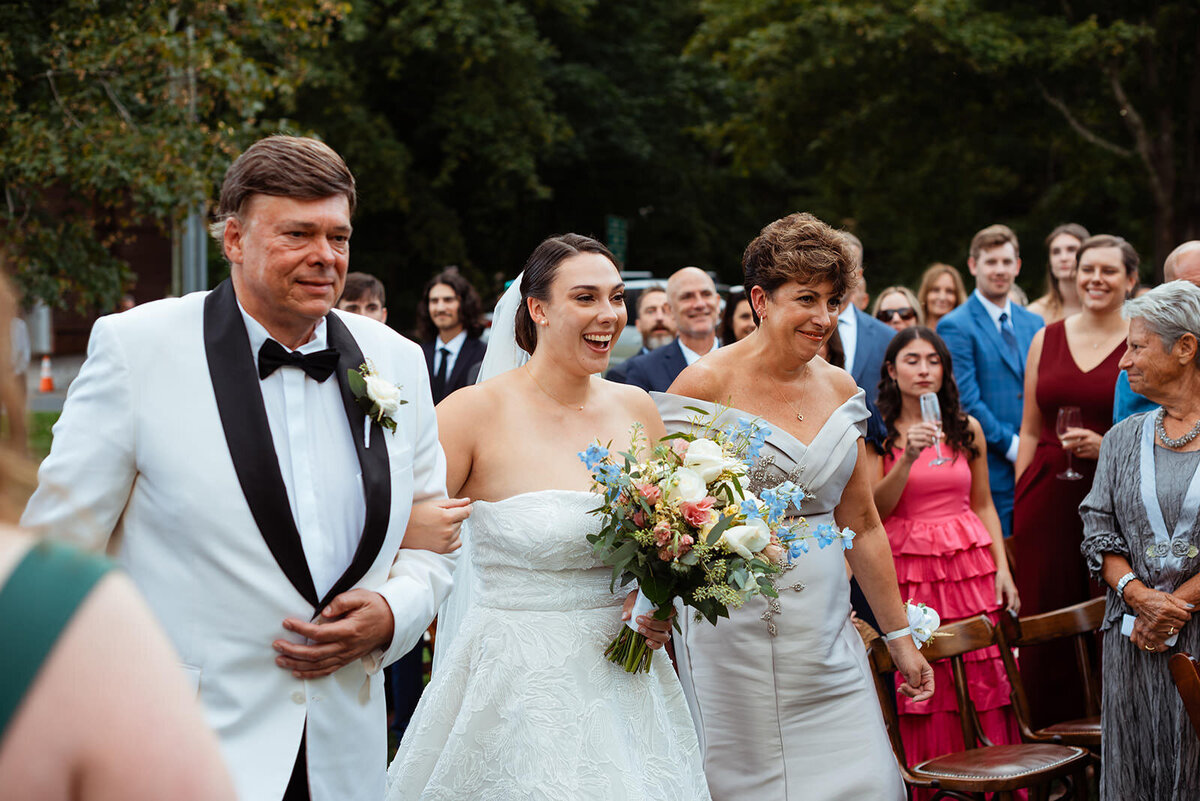 Bride walking down aisle with her parents hand in hand