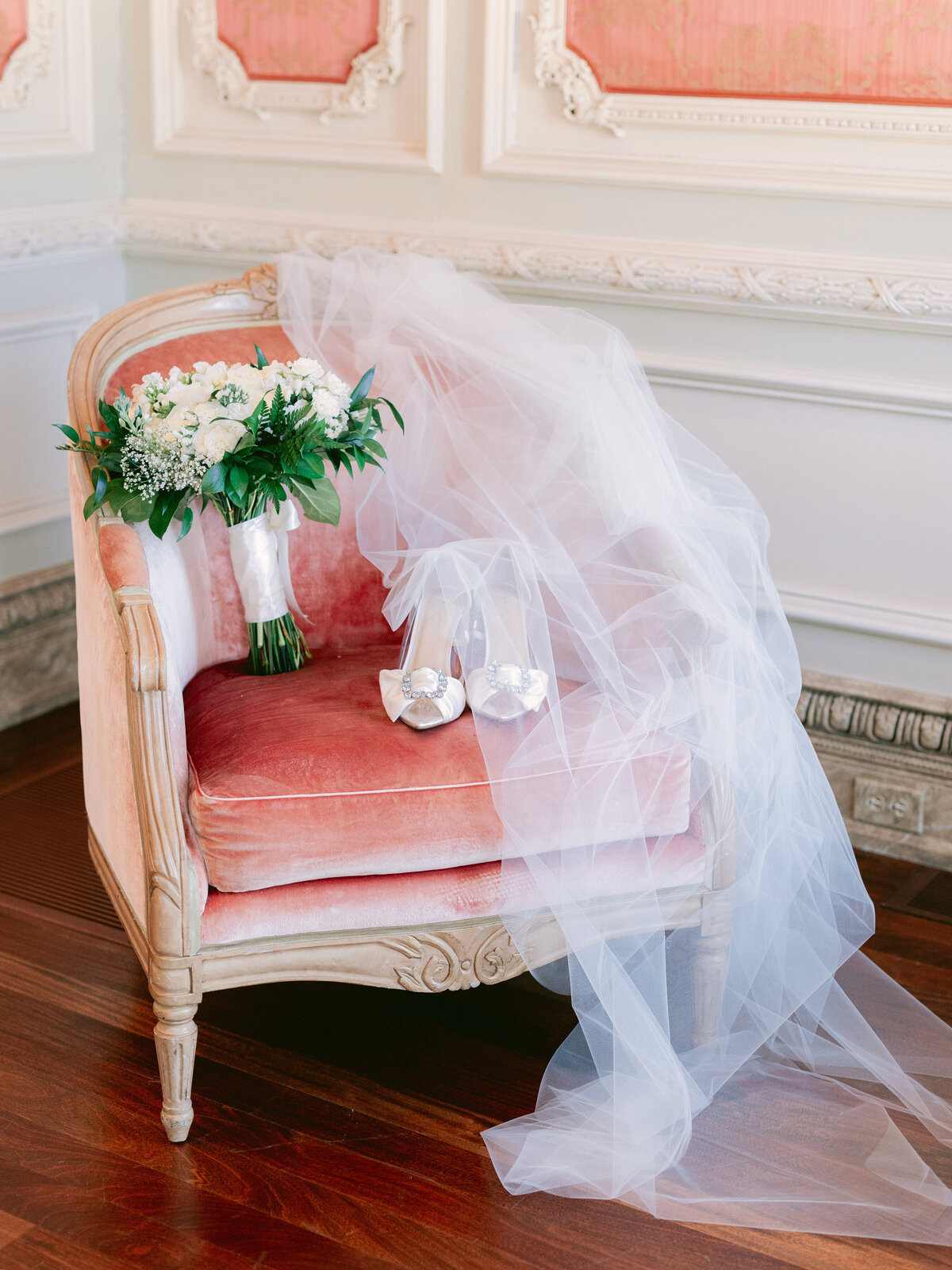 Luxurious arm chair displaying bridal veil, floral bouquet and shoes