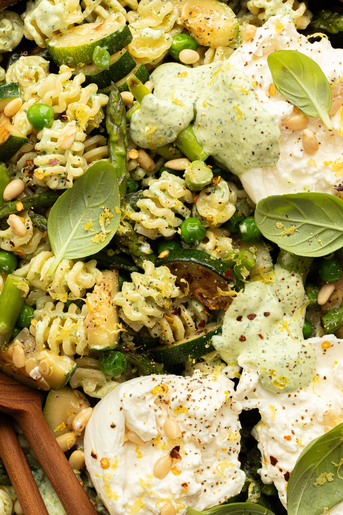 close up of a bowl of pasta salad topped with basil leaves