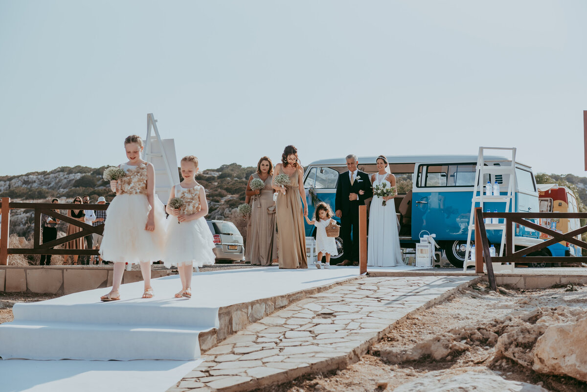 Bridal Party walking towards the ceremony after arriving in a blue VW campervan