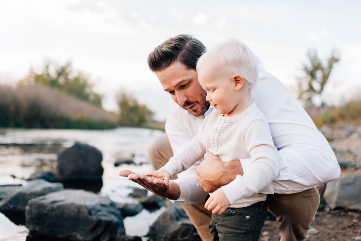 dad and boy playing in the water besides the denver river