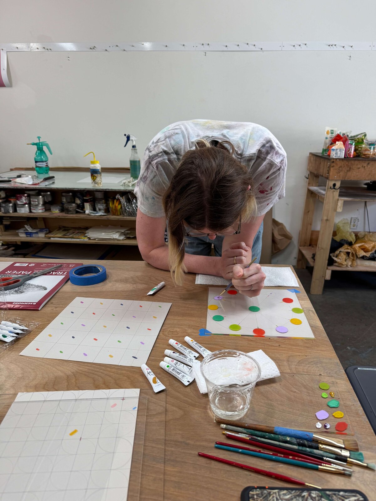 A participant bends over her grid to paint colorful circular patterns during the monoprinting workshop at Moonlight Press.