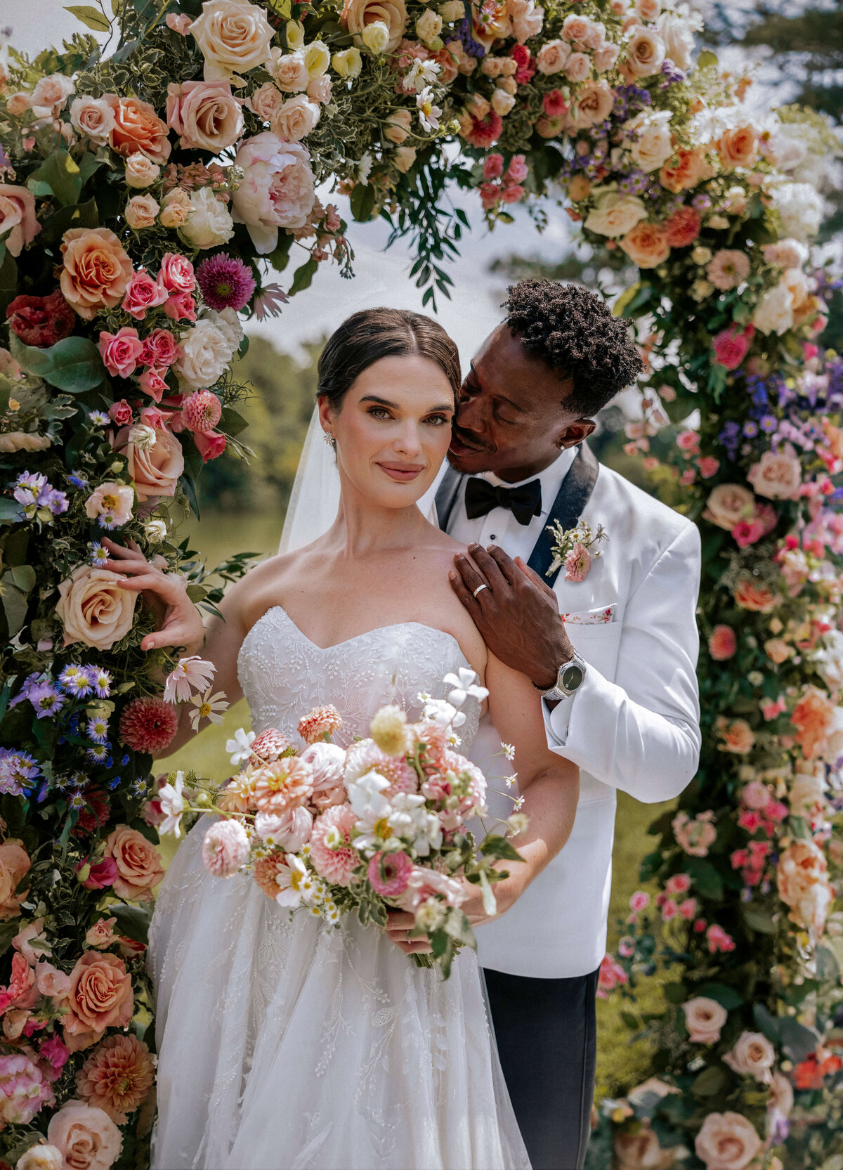 mixed-race-bride-and-groom-under-colorful-floral-arch