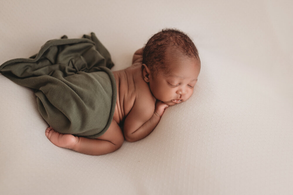 Newborn photos with Atlanta, Georgia newborn photographer of sleeping baby boy with hands under chin draped in olive green fabric over his diaper.